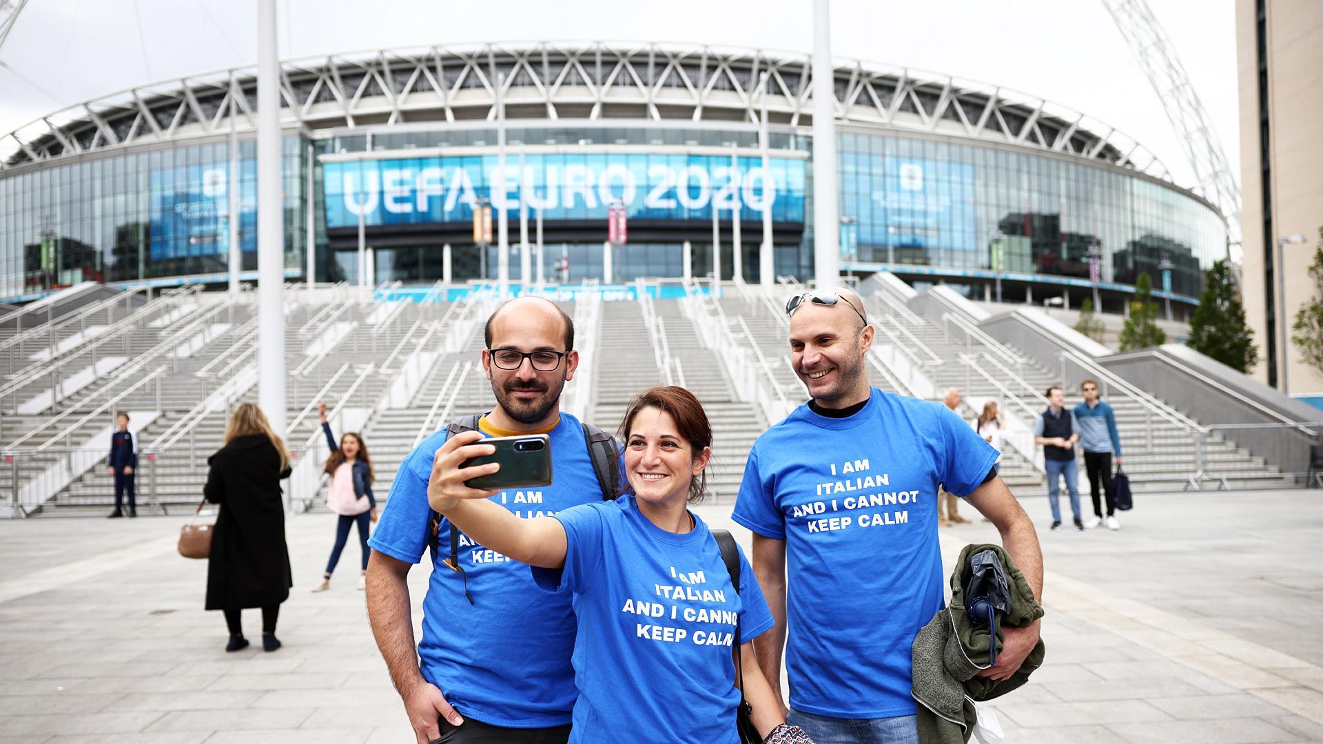 Aficiondos italianos se fotografían delante del estado de Wembley en la víspera de la final entre Inglaterra e Italia