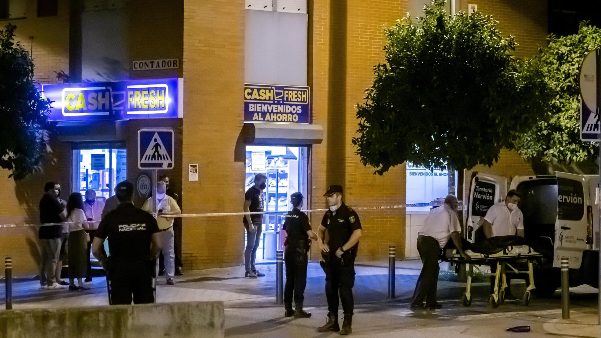 Los servicios funerarios transportan el cadáver de un hombre que ha muerto esta tarde por disparos de la Policía cuando estaba intentado atracar un supermercado de Sevilla