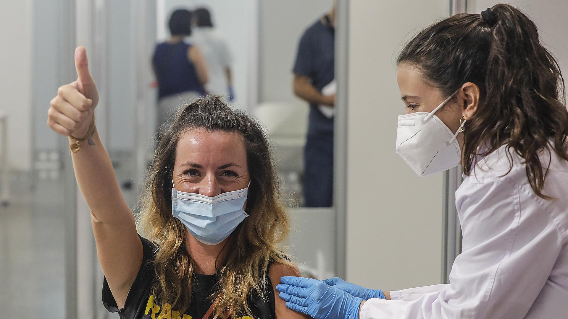 Una joven sonríe y saluda mientras recibe la vacuna contra la Covid-19 de la Ciutat de les Arts i les Ciències de Valencia