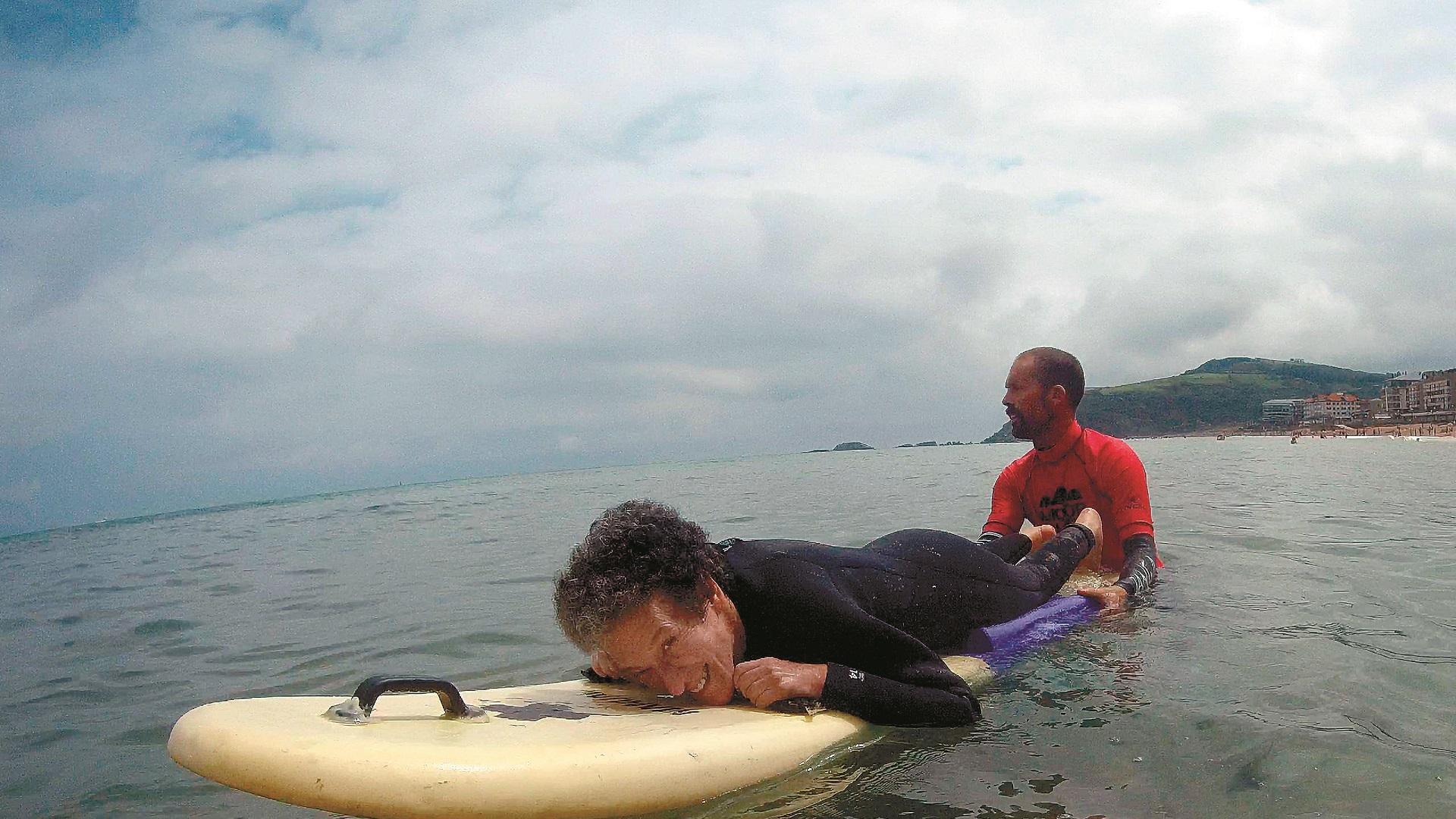 Marian Cano, tumbada sobre una tabla de surf, con un monitor de ‘MOOR Surf Eskola’, en Zarautz (Guipúzcoa), el pasado 3 de julio