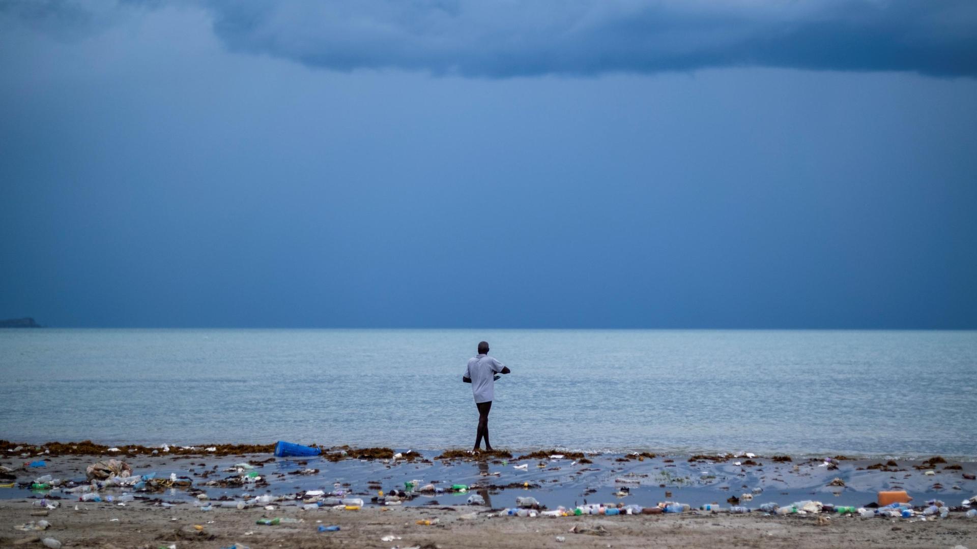 Un hombre pasea por una playa contaminada mientras la tormenta tropical "Grace" se aproxima