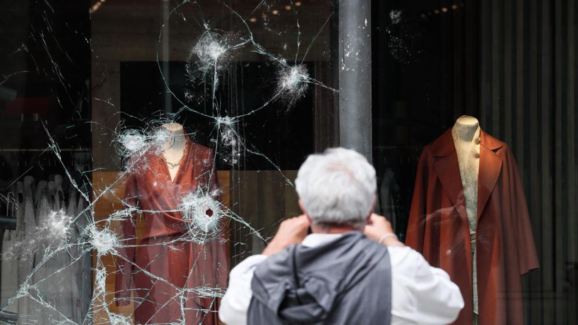 Un hombre observa un escaparate atacado durante la noche en el centro de San Sebastián