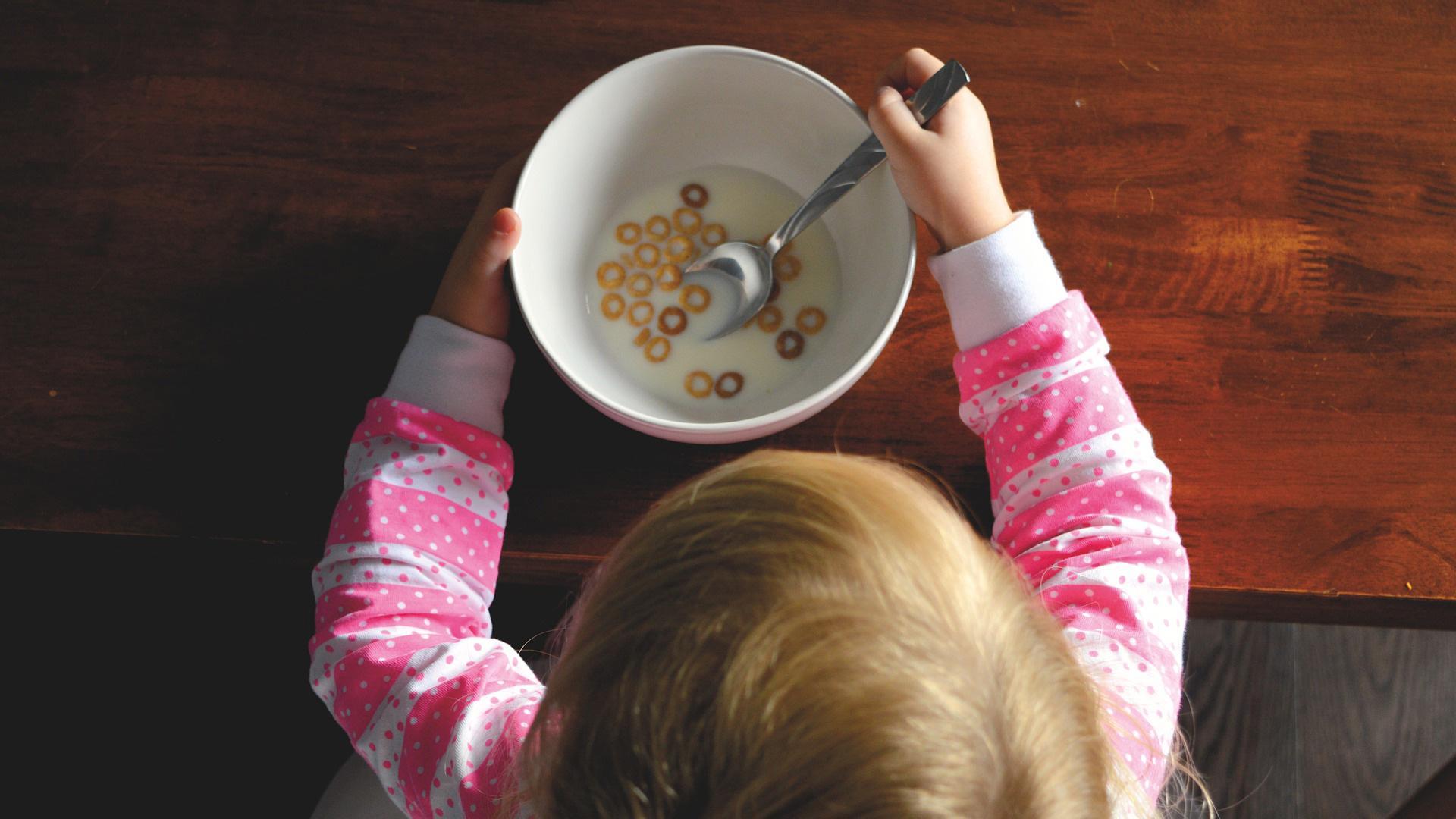 Imagen de un menor junto a un bol de cereales.