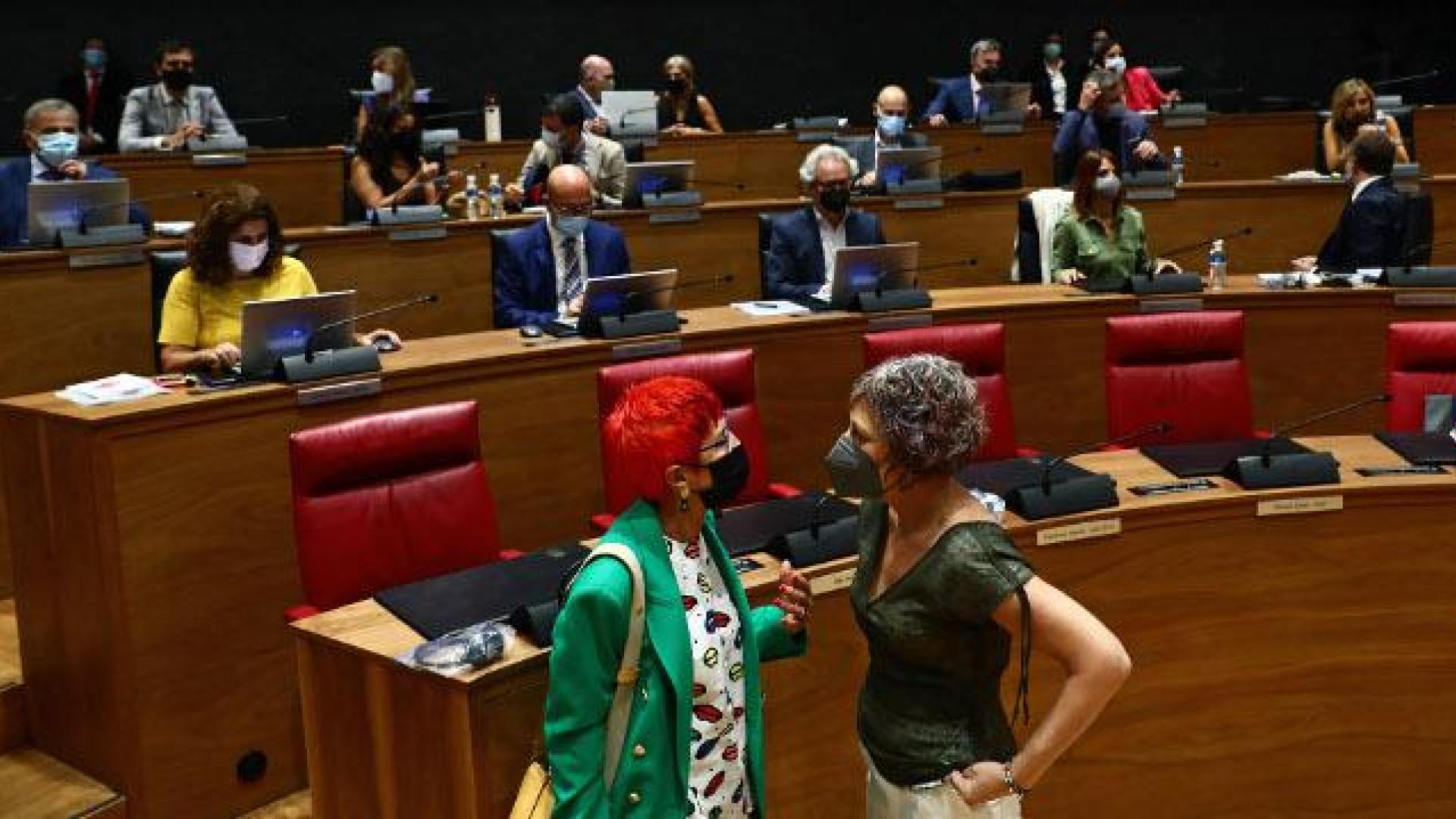 Las consejeras Santos Induráin (Salud) y Rebeca Esnaola (Cultura) hablan junto a los escaños de Navarra Suma en el hemiciclo