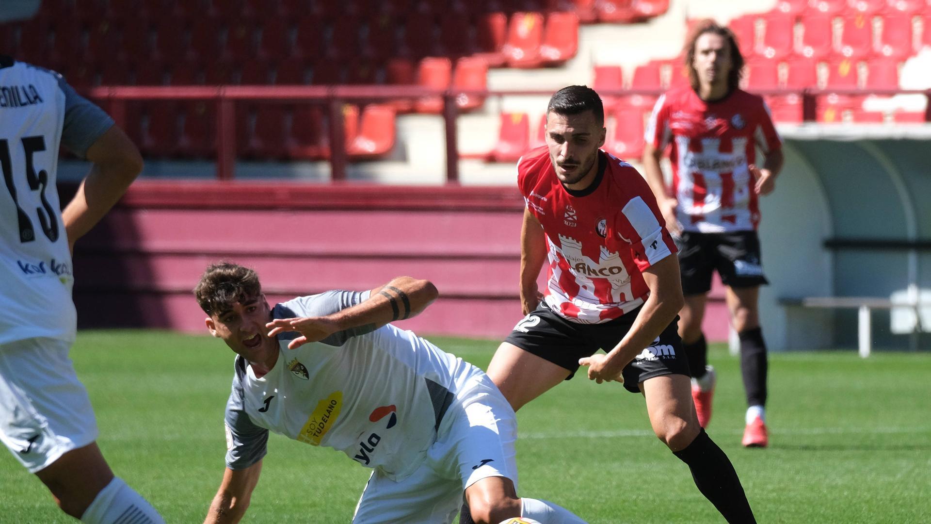El centrocampista del Tudelano Alain Ribeiro protesta desde el suelo ante Álvaro Arnedo