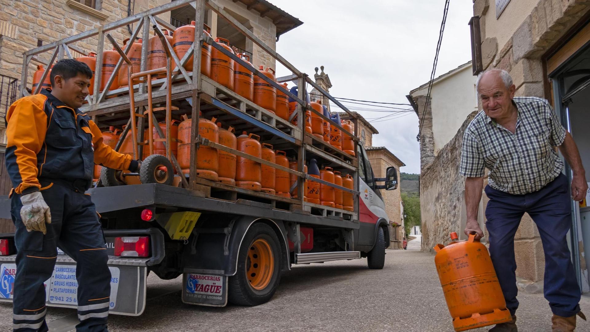 Un repartidor de bombonas tradicionales de Repsol entrega una  a Javier Urabayen Gil, de 78 años, en el pueblo de Luquin (Tierra Estella)