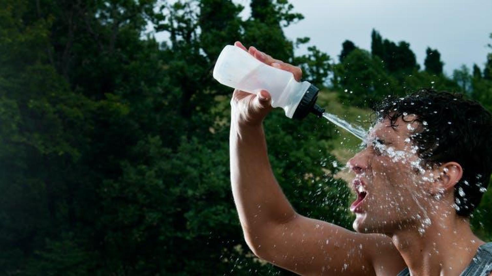 Un deportista, echándose agua