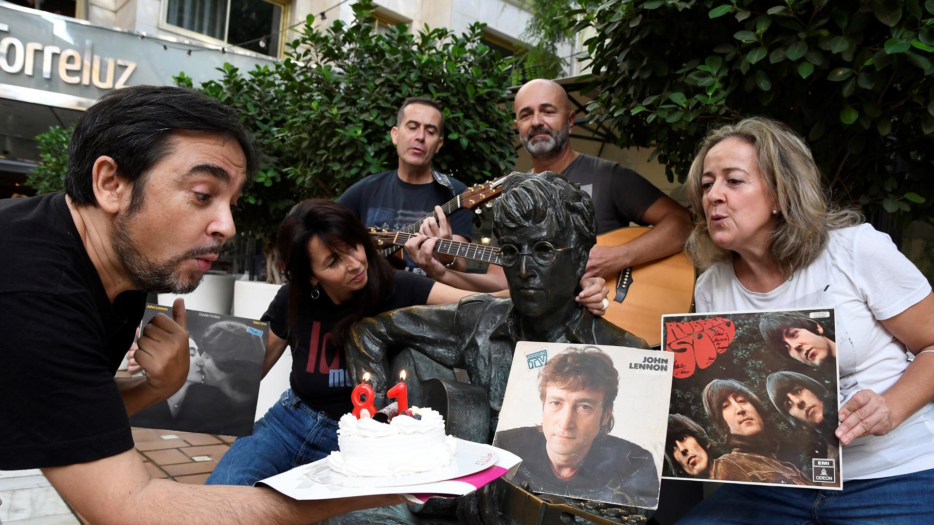 El periodista Adolfo Iglesias, autor del libro 'Juan y John, el profesor y Lennon en Almería para siempre' celebra junto a varios aficionados a los Beatles, el 81 cumpleaños del John Lennon, frente a la estatua del musico inglés en Almería.