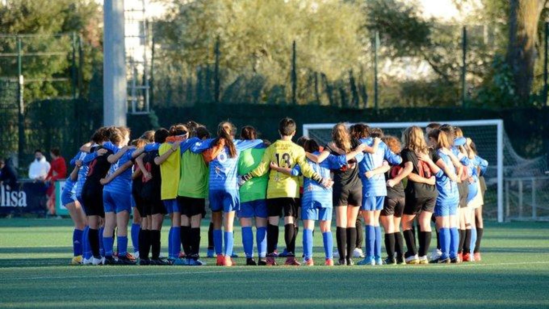 Las jugadoras de los dos equipos, abrazadas en el centro del terreno de juego