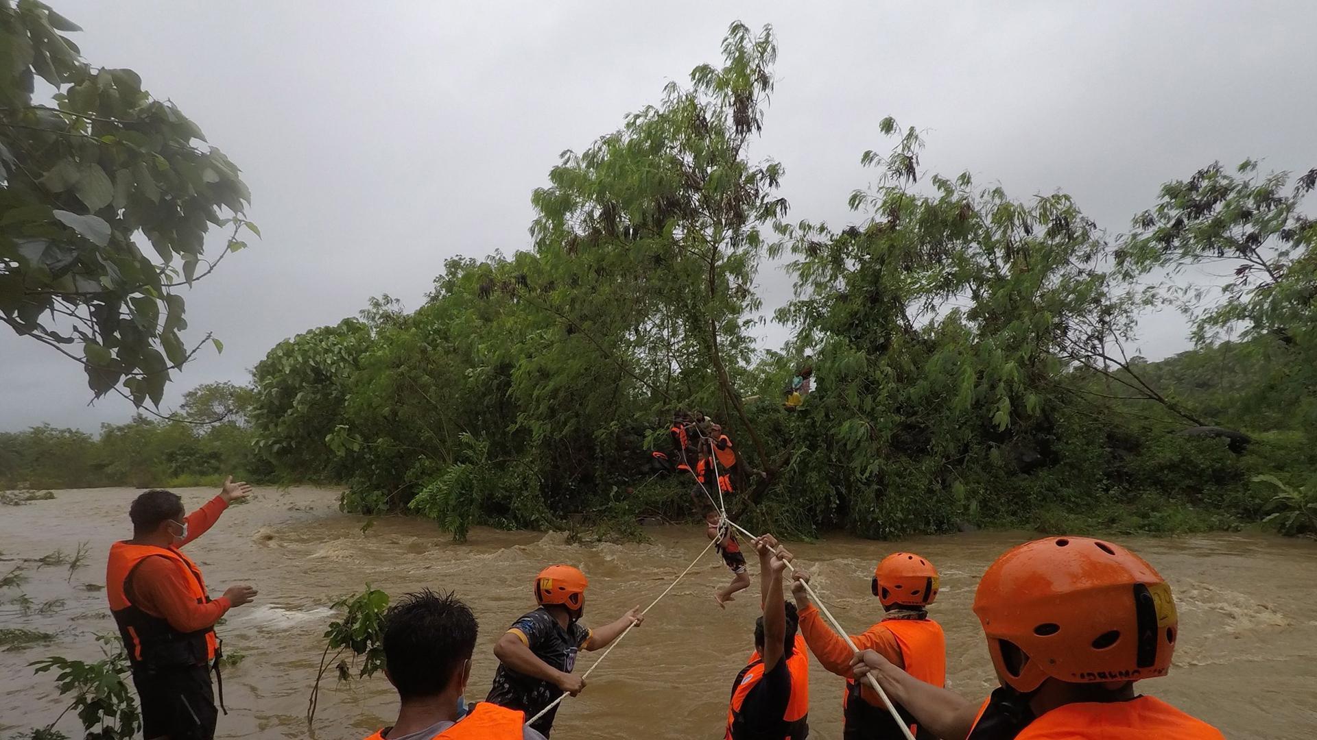 Equipos de rescate ayudan a una persona a pasar sobre un río en la provincia filipina de Gonzaga