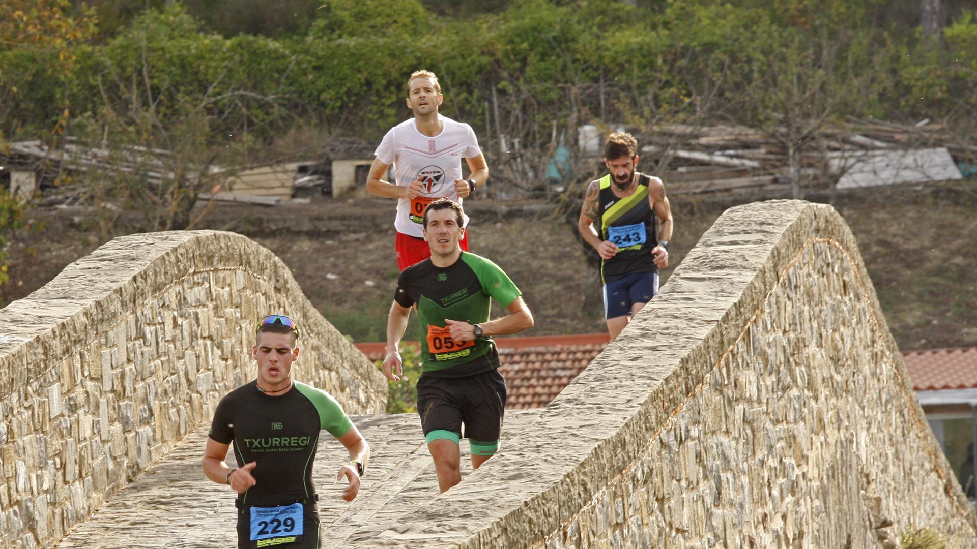 Un grupo de corredores, cruzando el puente ya de regreso a Aoiz tras recorrer las laderas cercanas