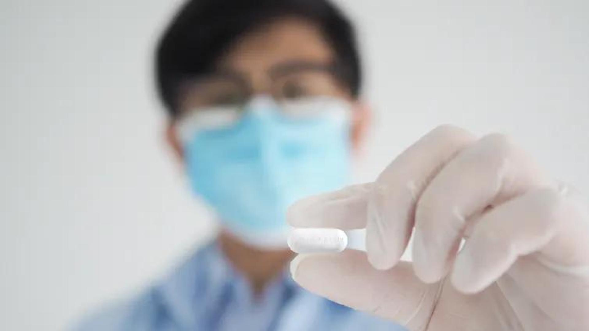 Un sanitario sostiene una pastilla de Molnupiravir