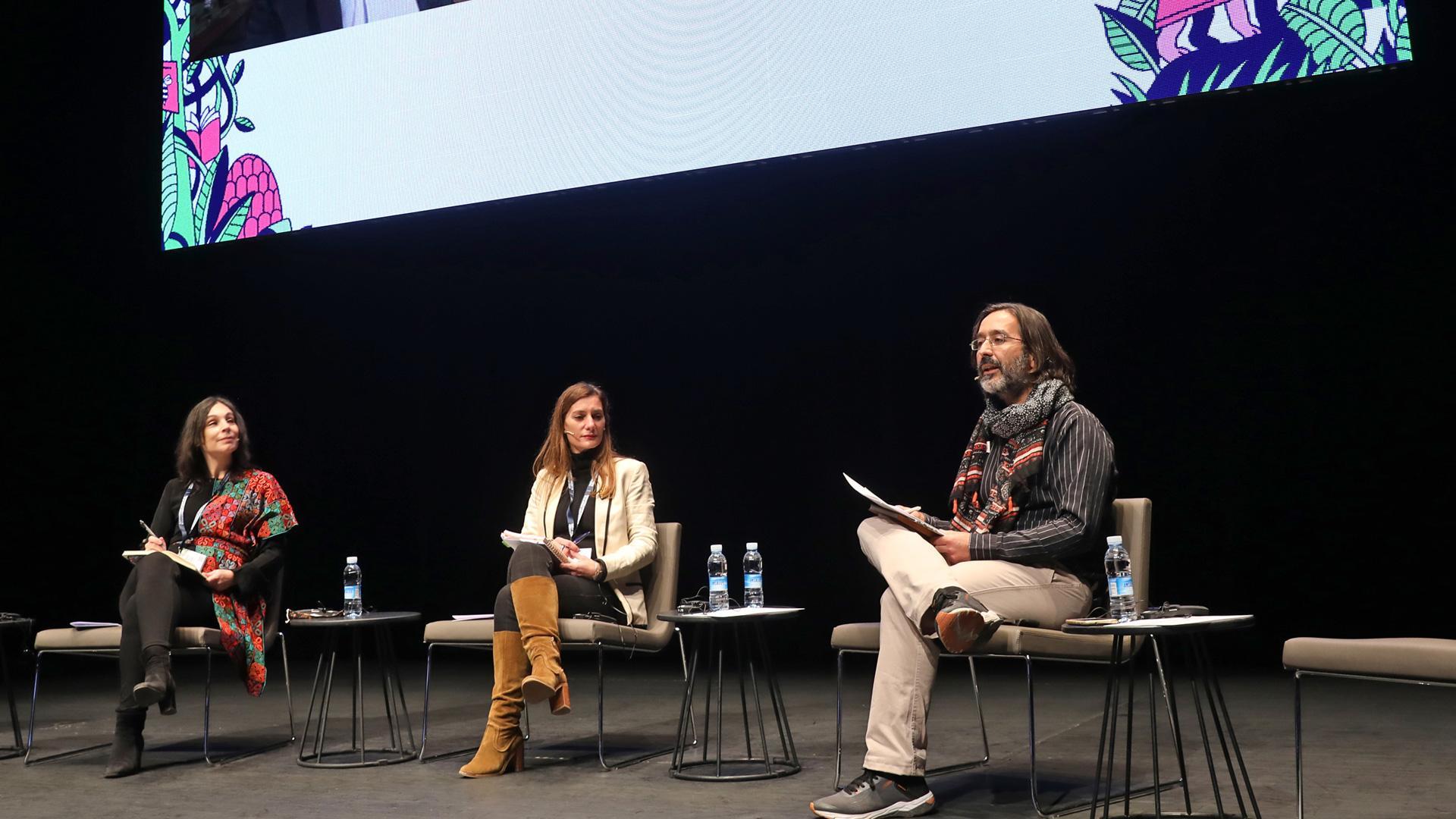 De izda. a dcha.; la editora marroquí Kenza Sefrioui, la francesa Esther Merino y el moderador Alfonso Serrano. En pantalla, de izda. a dcha,; Julien Lefort-Favreau y John B. Thompson