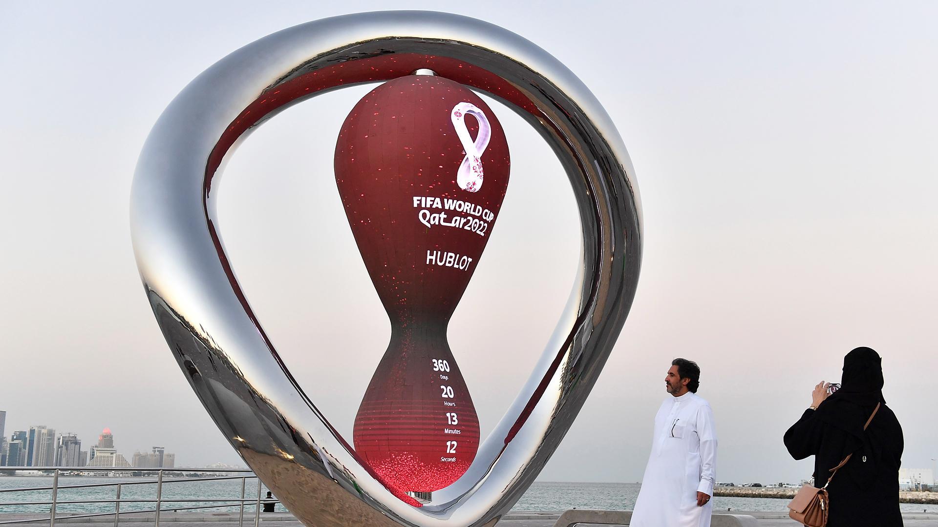 Dos personas se fotografían junto a un reloj de arena con al cuenta atrás para el comienzo del Mundiat de Catar 2022 en Doha
