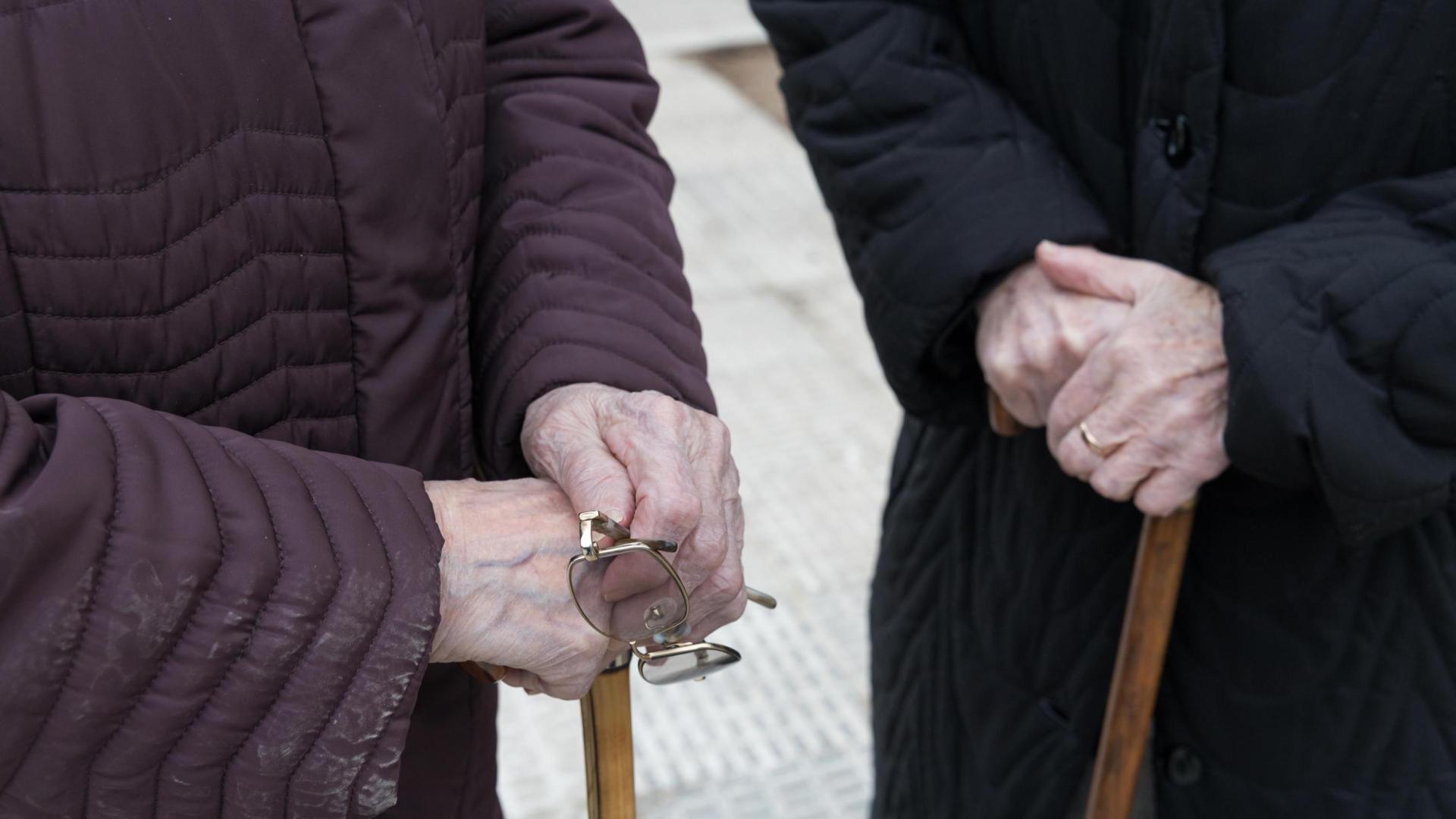 Dos señoras mayores se apoyan en sendos bastones, a las puertas del hospital Reina Sofía