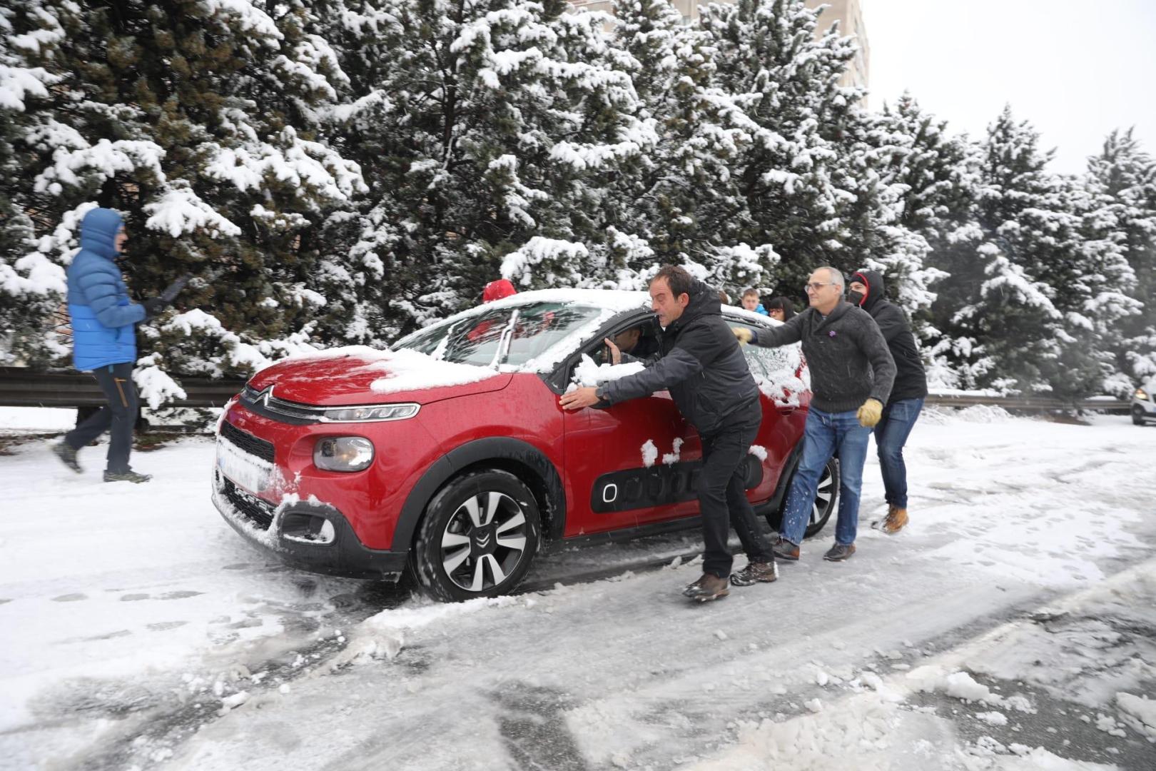 Varias personas ayudan a los vehículos atrapados en la avenida de Navarra