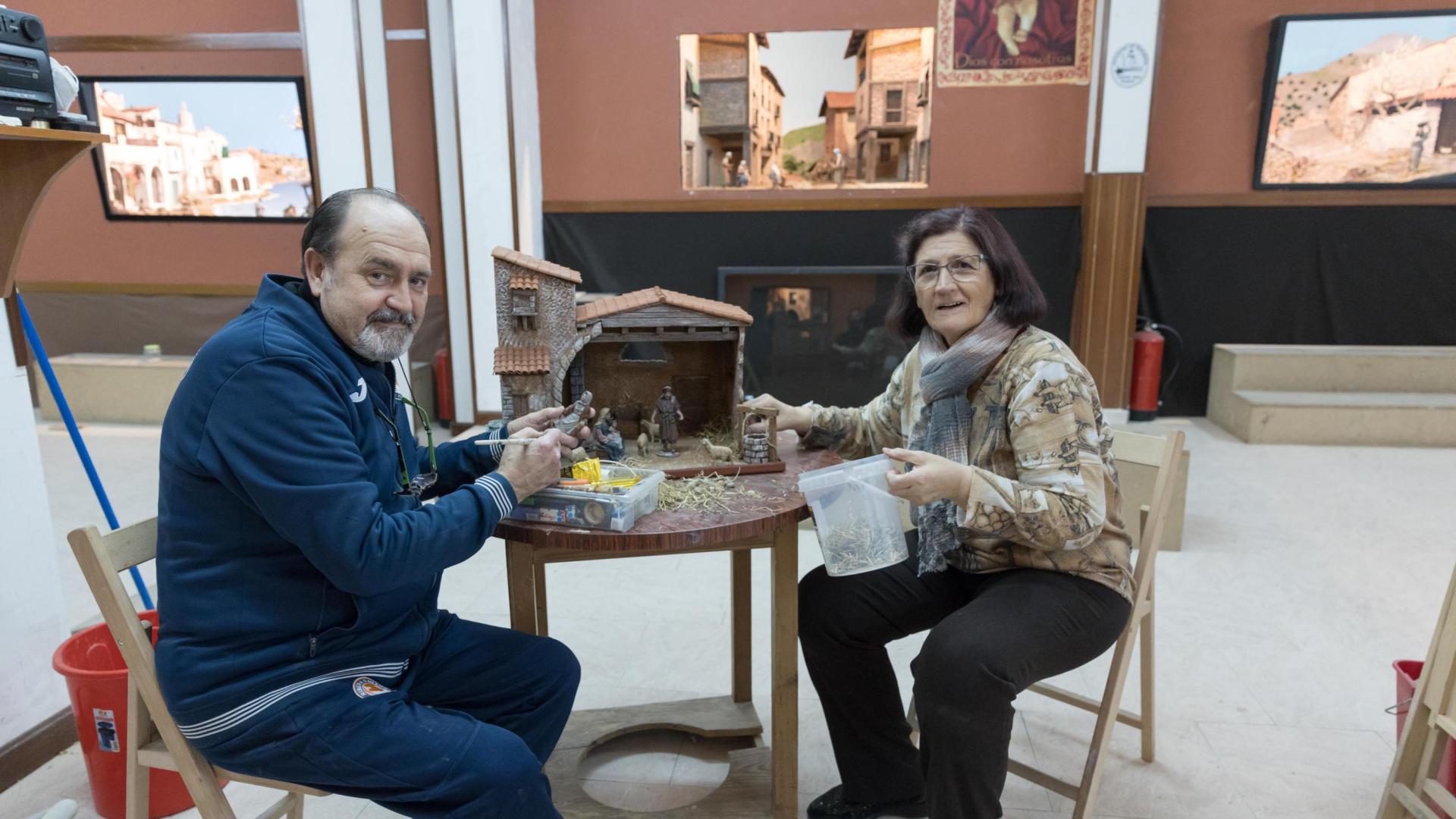 Félix Merino y Marisa Barrena trabajan en un Portal de Belén y ante tres de los dioramas que integran la exposición