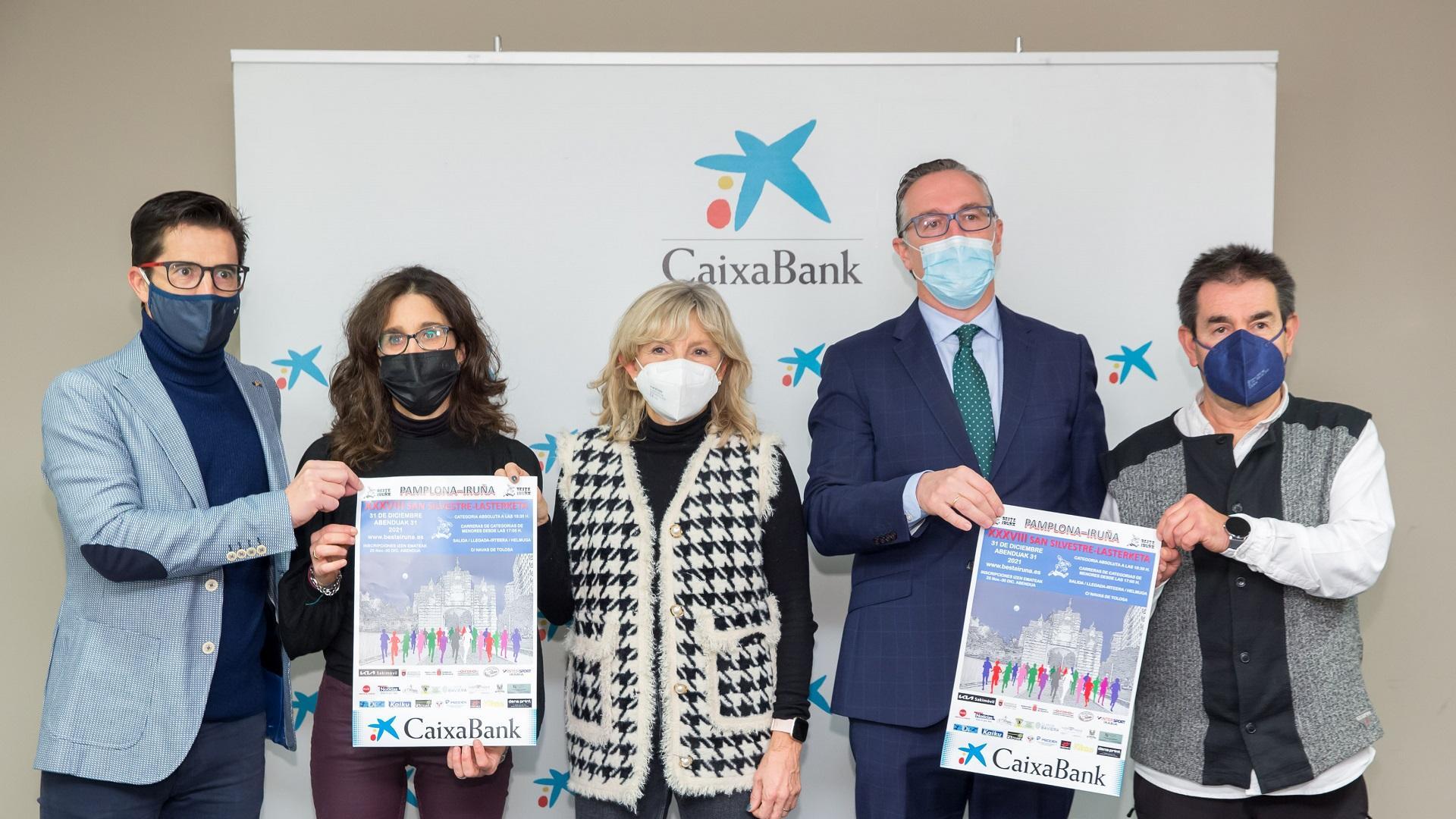 Rodrigo Domínguez, presidente de la Federación Navarra de Atletismo; Marisol Aspurz, representante del Beste Iruña, club organizador de la prueba; María Caballero, concejala de Asuntos Sociales del Ayuntamiento de Pamplona; Miguel Navarrete, director del Centro de Instituciones de la Territorial Ebro de CaixaBank; y Primitivo Sánchez, subdirector de Deporte del INDJ, con el cartel de este año