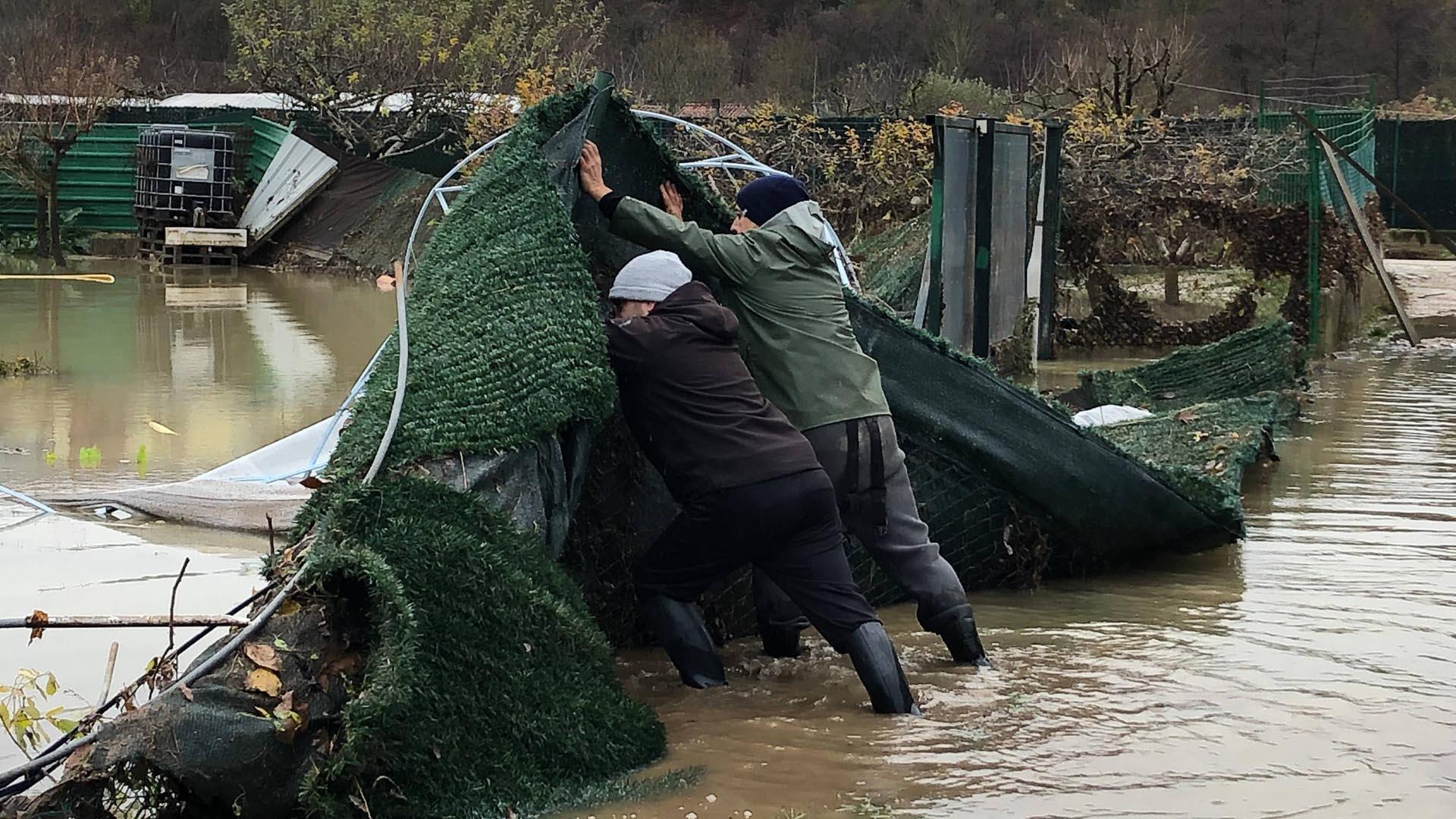 Josetxo Garralda Guerrero, con gorro gris, ayuda a su padre a levantar una parte de la valla arrastrada por el río Arga a su paso por las huertas de Zokoa en Huarte