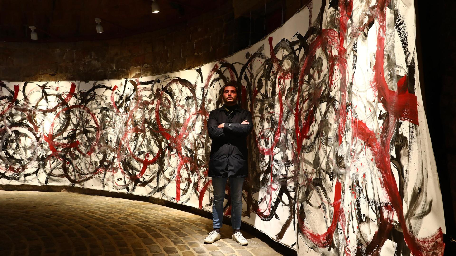 Yago Vaillo junto a la obra creada para el Horno, que ha pintado con la ayuda del movimiento de los pies de una bailarina de ballet.