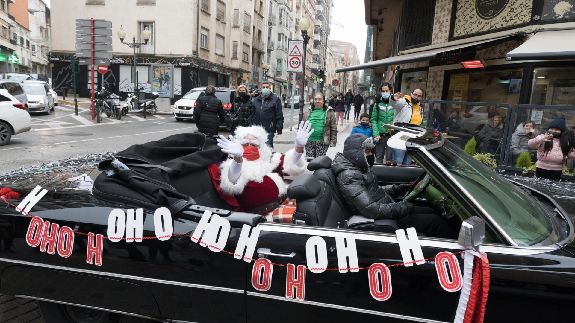 Papá Noel saluda desde su coche descapotable durante su recorrido por Tudela