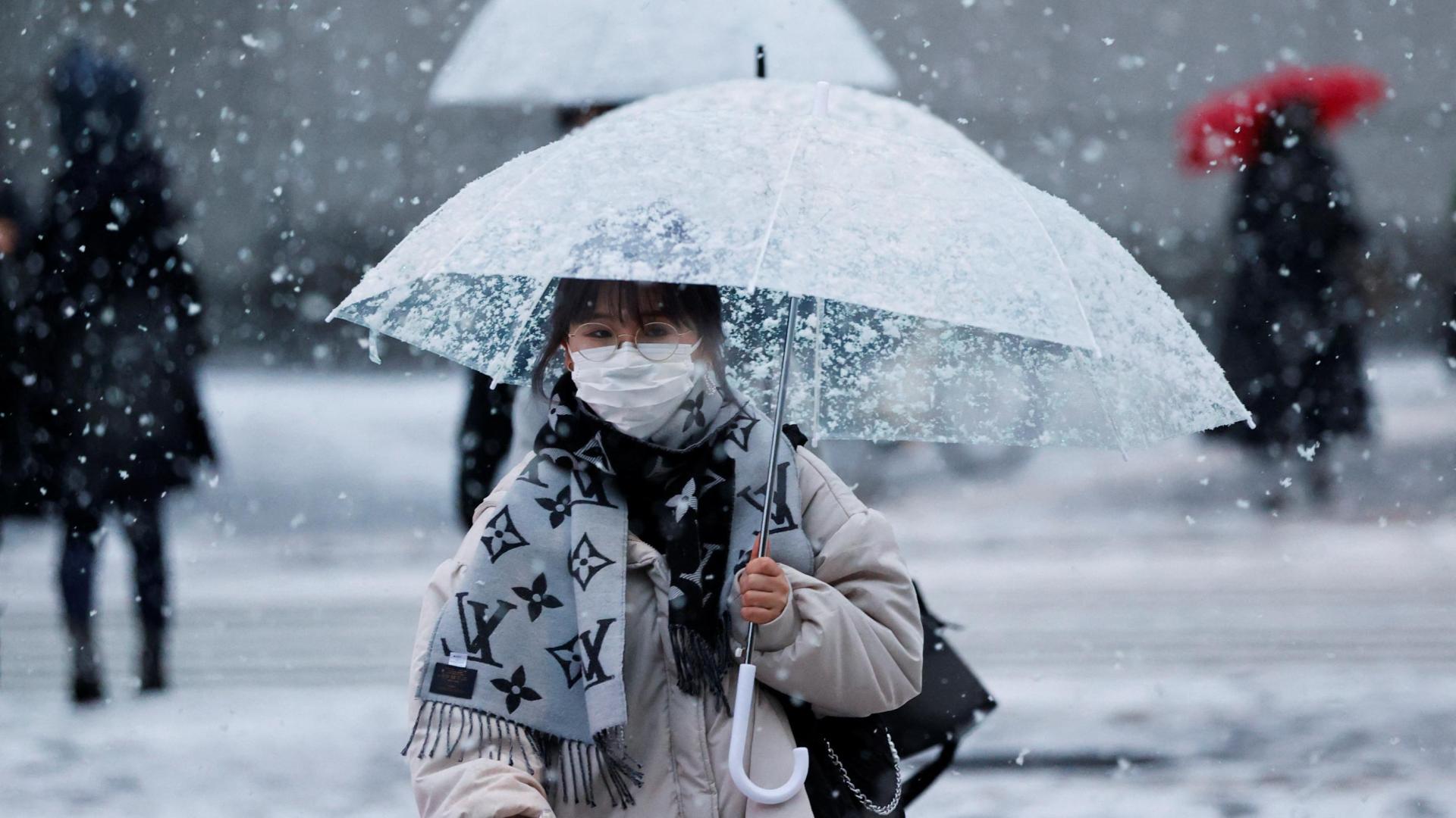 Una mujer con una mascarilla en una calle nevada en Tokio