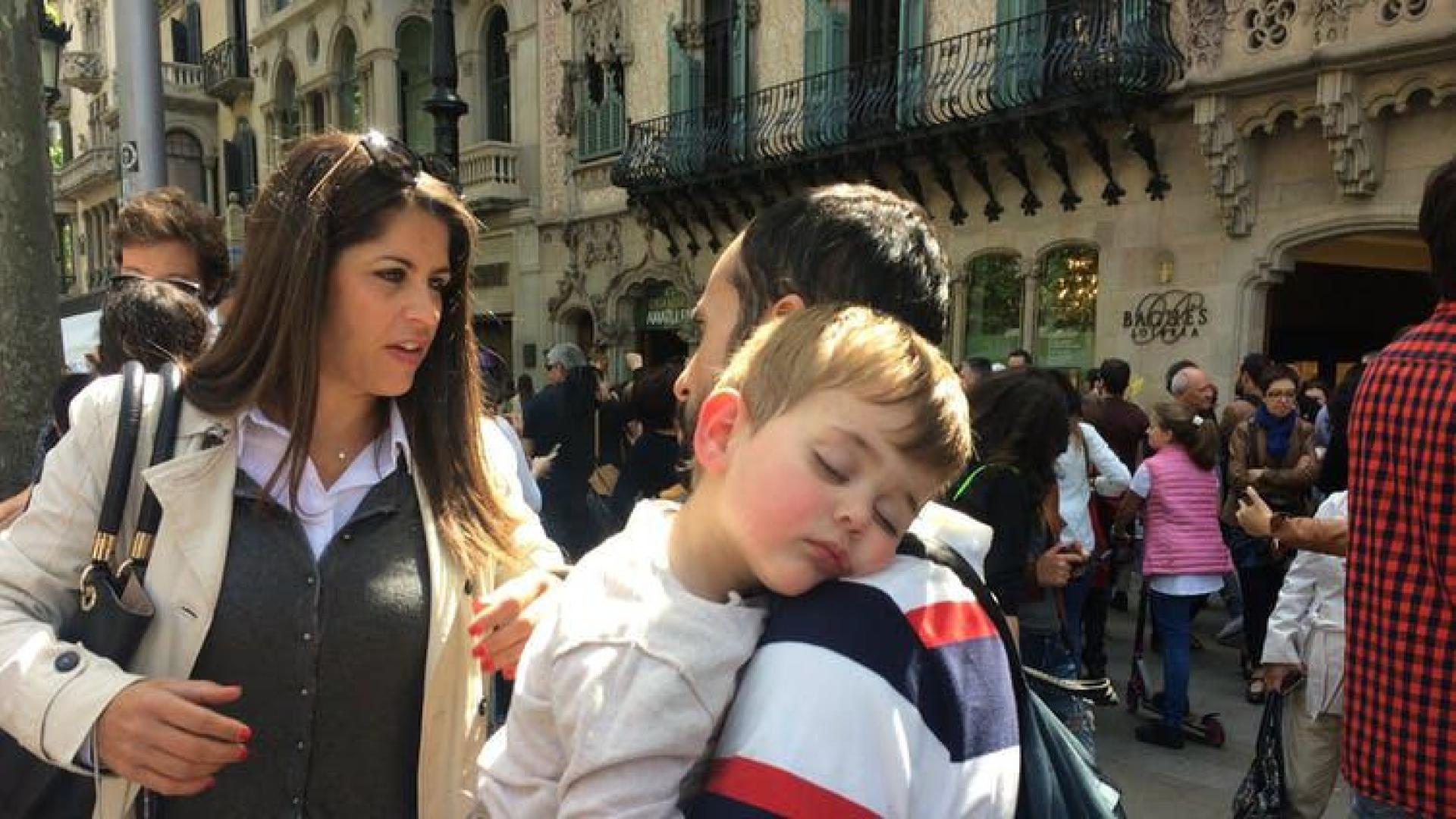 Niño dormido en brazos de un adulto junto a la Casa Batlló, en Barcelona, en 2017