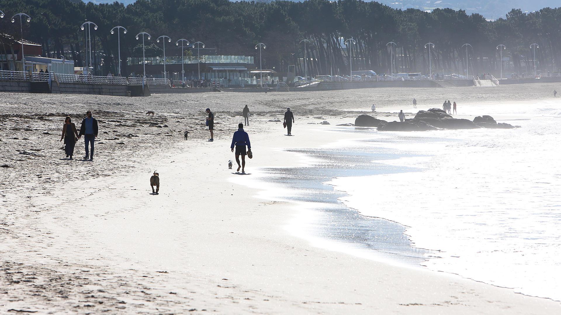 Varias personas caminan este martes en la playa de Samil de Vigo en una jornada soleada