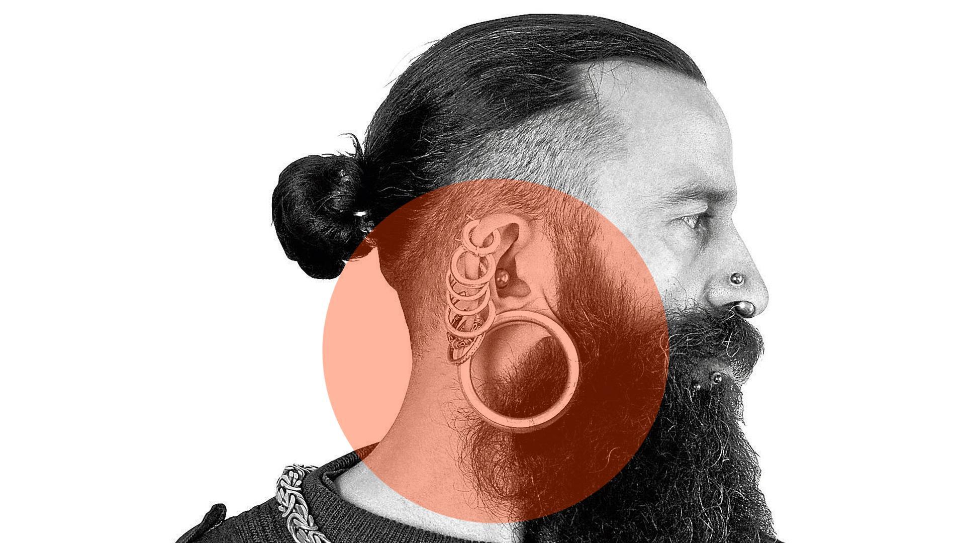 Un hombre con barba y varios pendientes