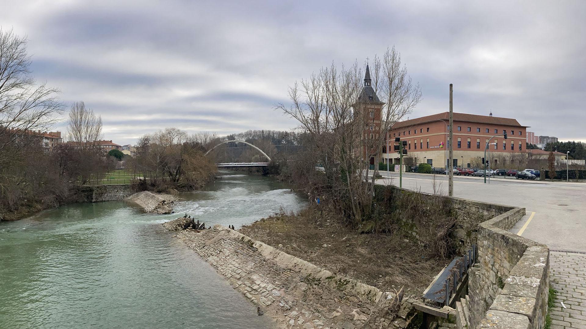 Viandantes por el puente de Santa Engracia, con el azud del mismo nombre en el río y partido por la mitad