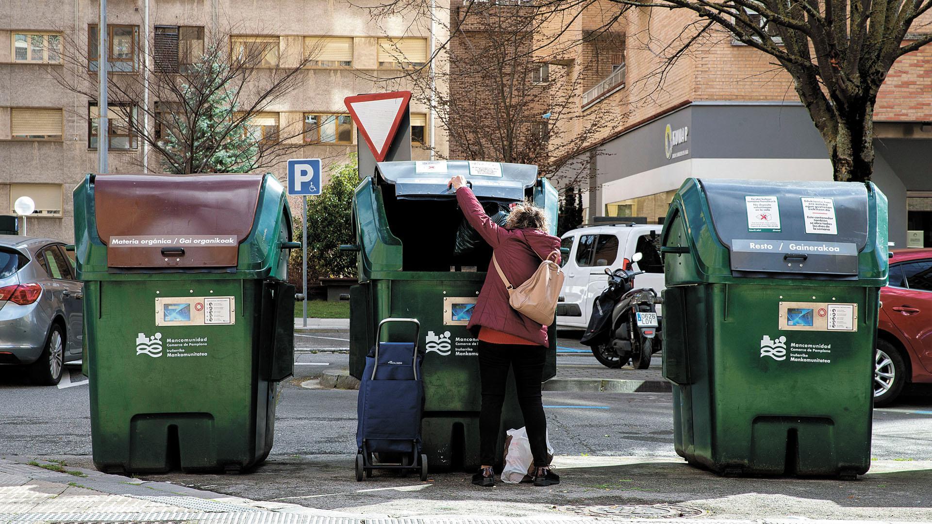 Una mujer deposita una bolsa en un contenedor en Pamplona