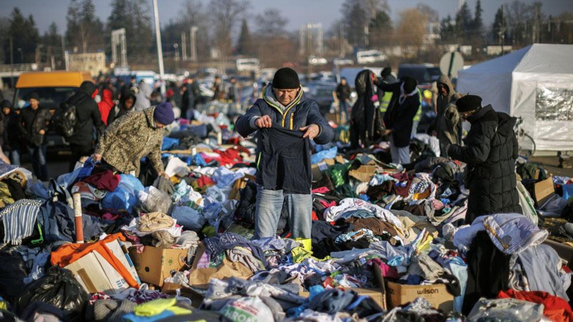 Una persona busca entre la cantidad de ropa donada para los ciudados procedentes de Ucrania que este domingo han cruzado la frontera con Polonia