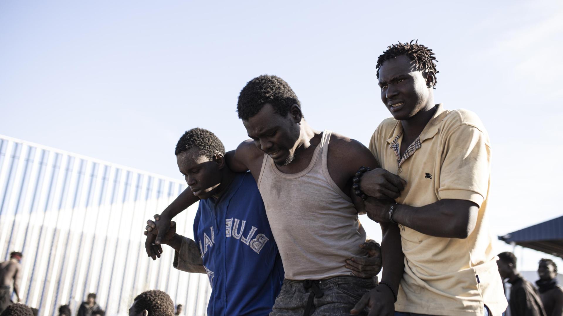Un migrante es ayudado por sus compañeros, tras conseguir saltar la valla de Melilla