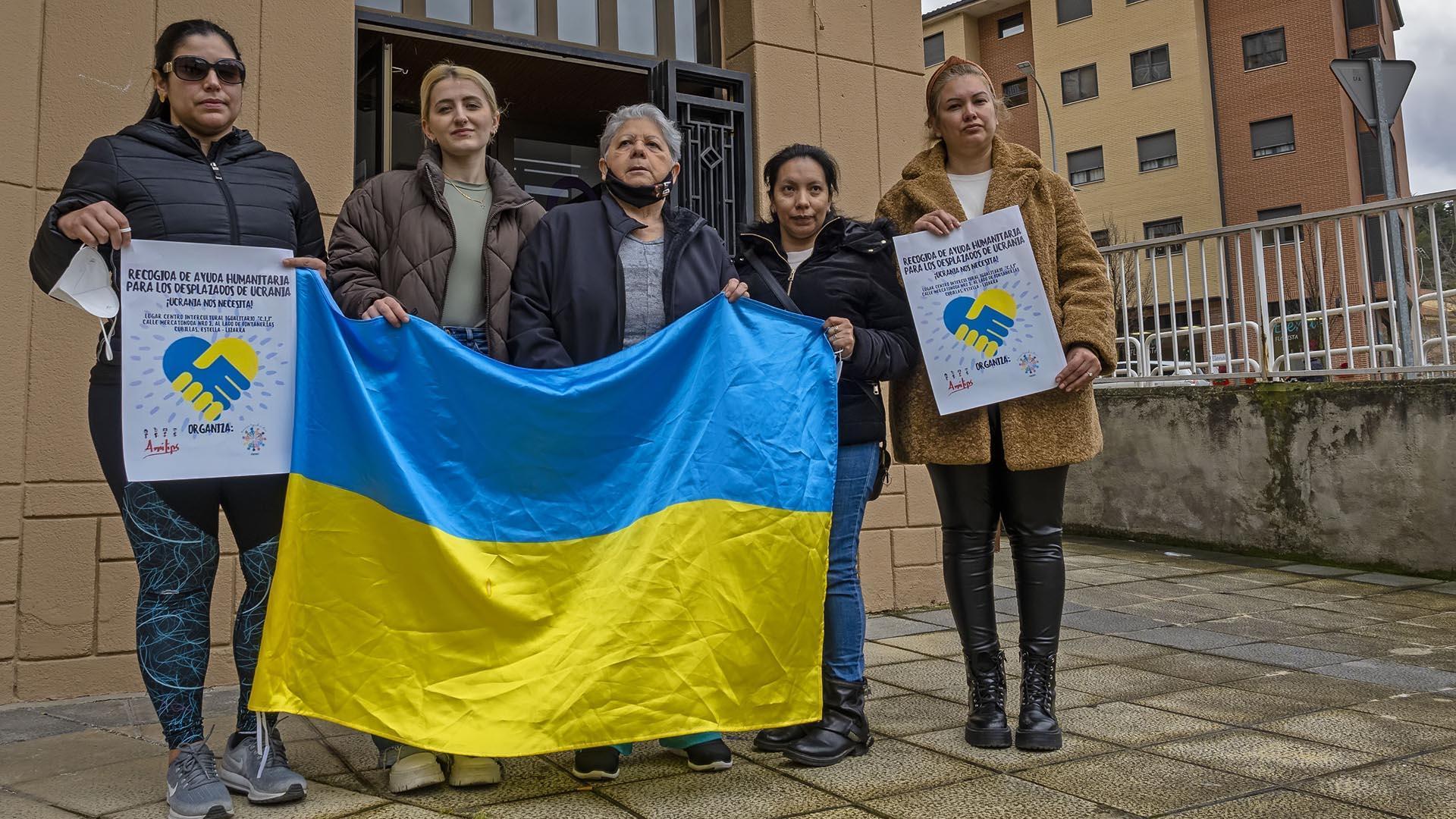 La ucraniana Olena Liber, con la bandera de su país arropada por Carolina Urbina, Romina Addamo y otras  mujeres de las asociaciones que colaboran con la recogida en su sede de Estella
