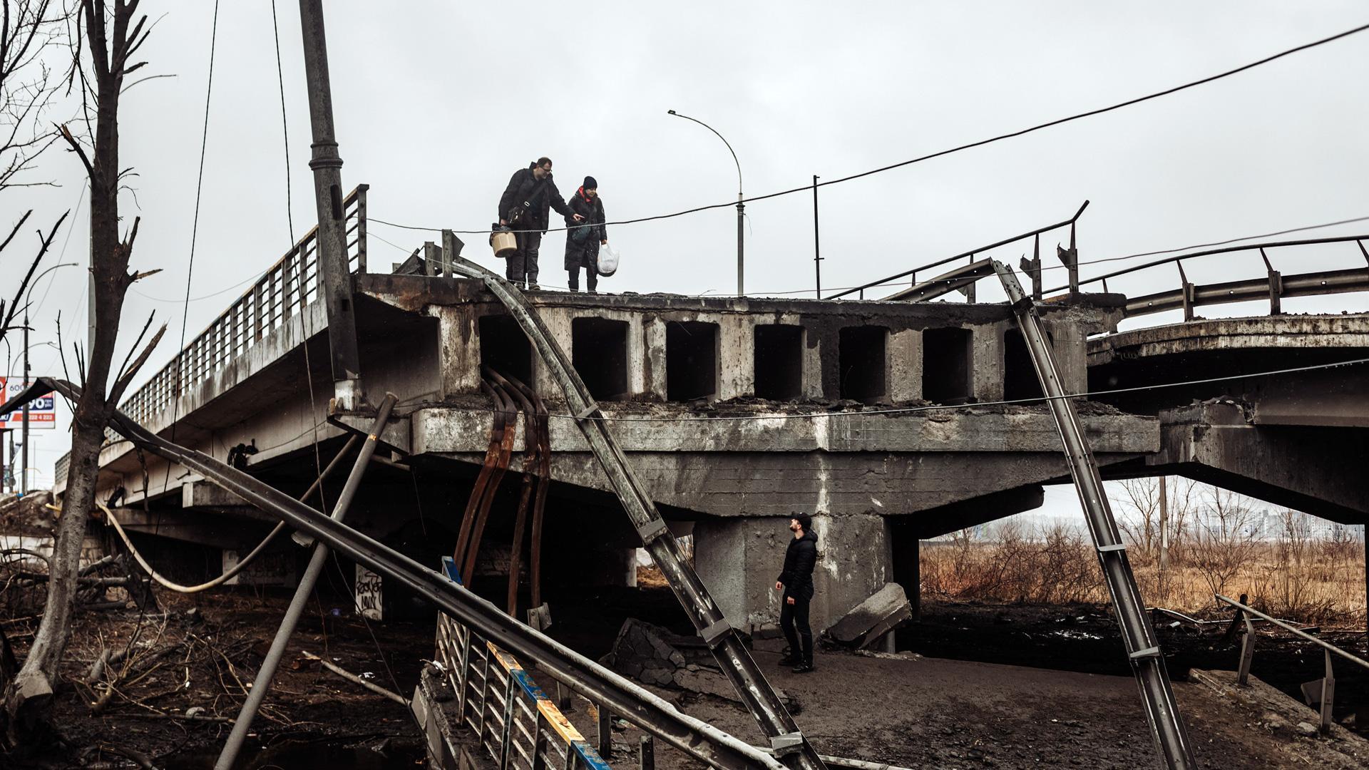 Varios civiles cruzan por el puente bombardeado en Irpin (Ucrania)