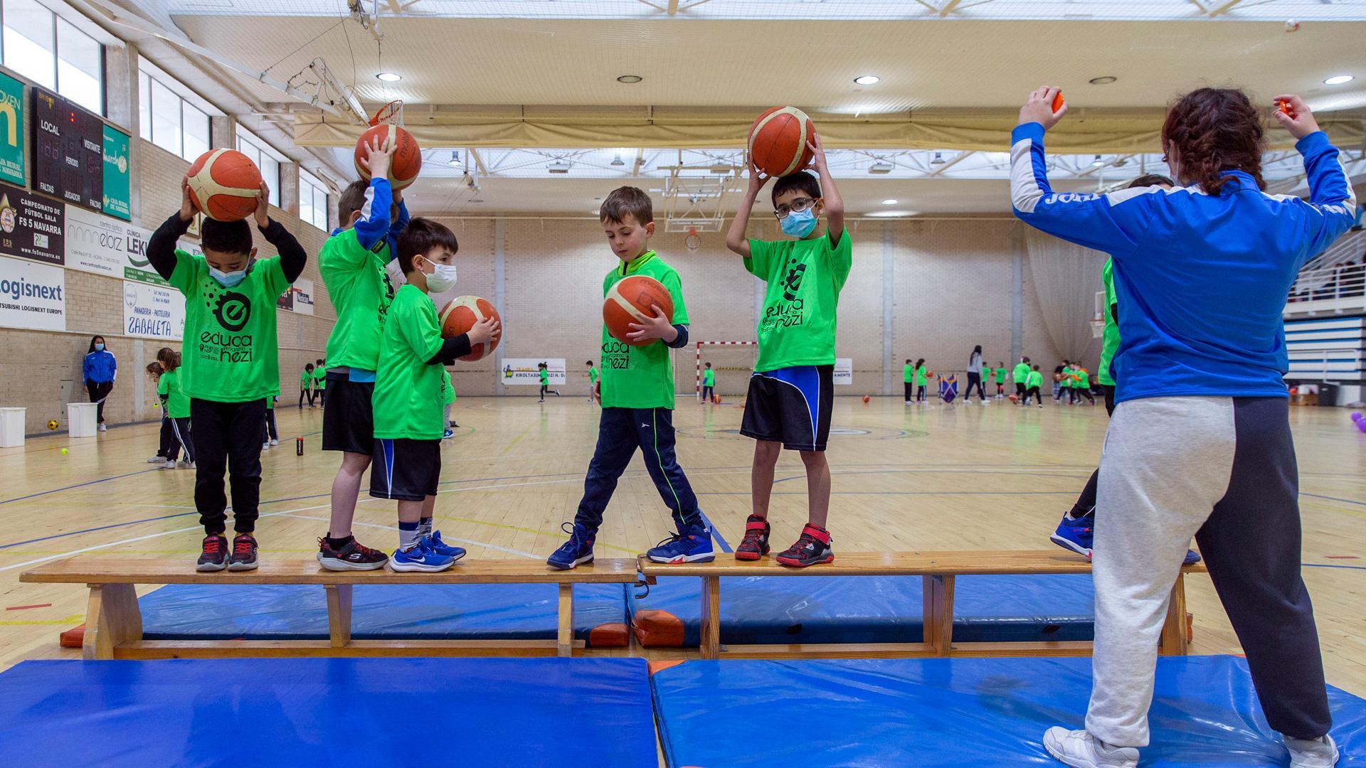 Seis escolares, de los sesenta participantes que hubo ayer en el Polideportivo Municipal de Noáin, practican el equilibrio supervisados por Nahia Ruiz, entrenadora del Club Baloncesto Noáin