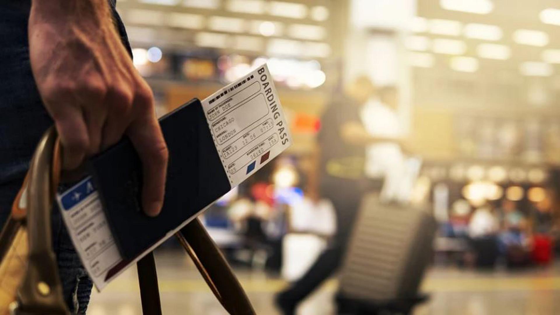 Una persona sostiene su pasaporte y el billete de avión