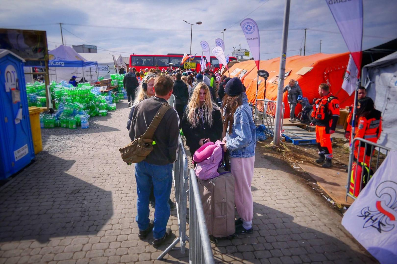 Ayuda en la frontera Un grupo de ucranianos hace cola a 250 metros de la frontera con Polonia (en Medyka). Desde allí, un autobús les llevará a la estación de tren en Przemysl, al sur del país. Y podrán proseguir su viaje para desplazarse a otra ciudad de Polonia o a algún país europeo. Militares, bomberos, policías y voluntarios les ofrecen ayuda, ropa y alimentos