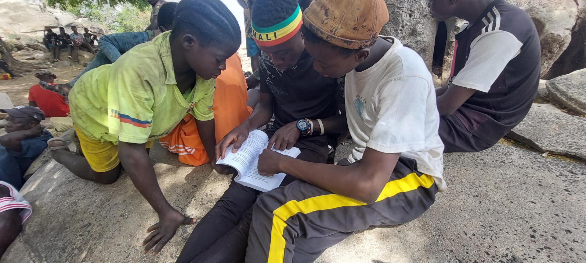 Tres niños leen los primeros cuentos escritos publicados en lengua bedik