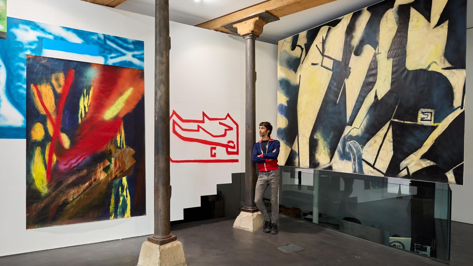 Taxio Ardanaz, junto a parte de las obras de la exposición en Apaindu. A sus espaldas, el  mural de gran formato que ha creado expresamente para el espacio expositivo.