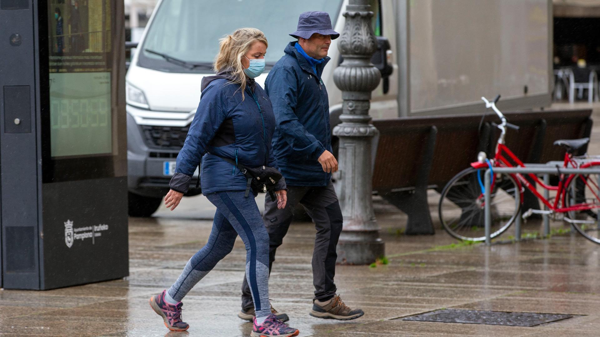 Dos personas por una calle de Pamplona, una de ellas con mascarilla y la otra no