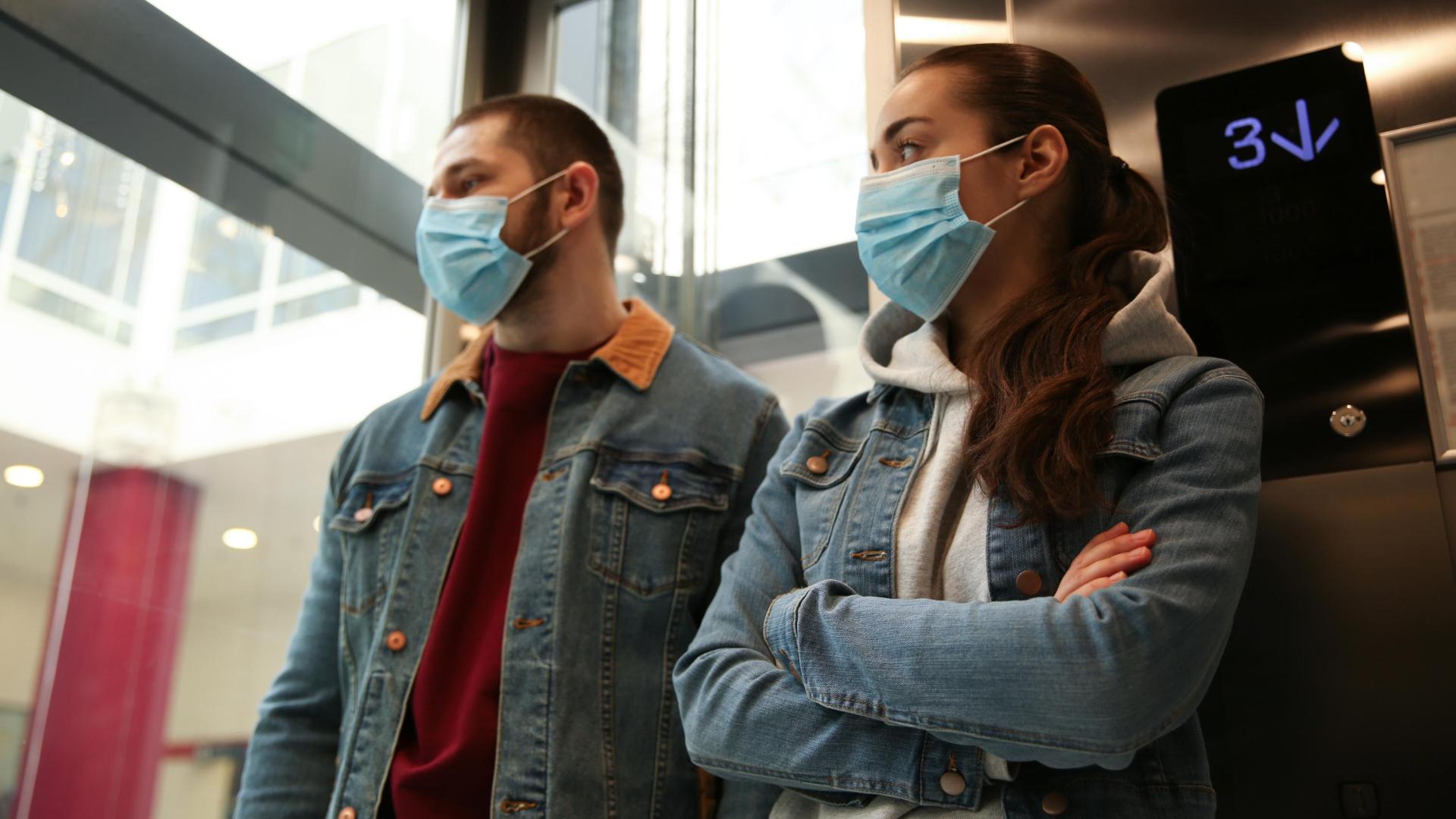 Dos personas con mascarilla en un ascensor