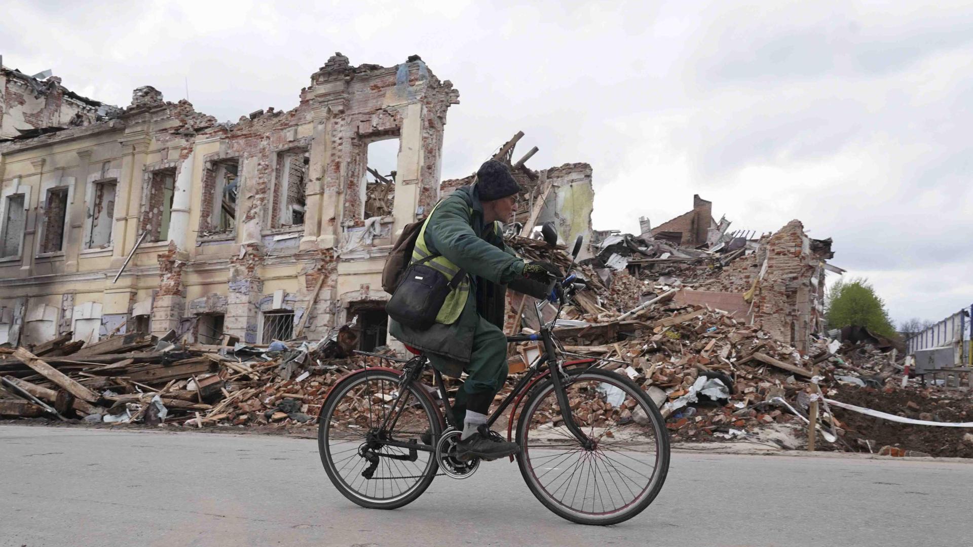 Un ucraniano monta en bicicleta frente a un edificio destruido en Kharkiv, Ucrania