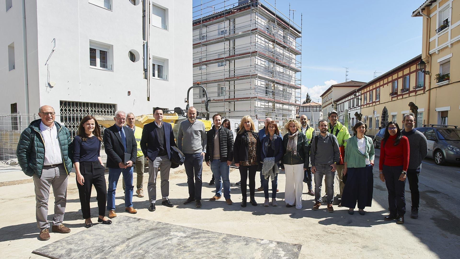 Representantes municipales y vecinos posan junto a las viviendas que serán rehabilitadas en la Txantrea