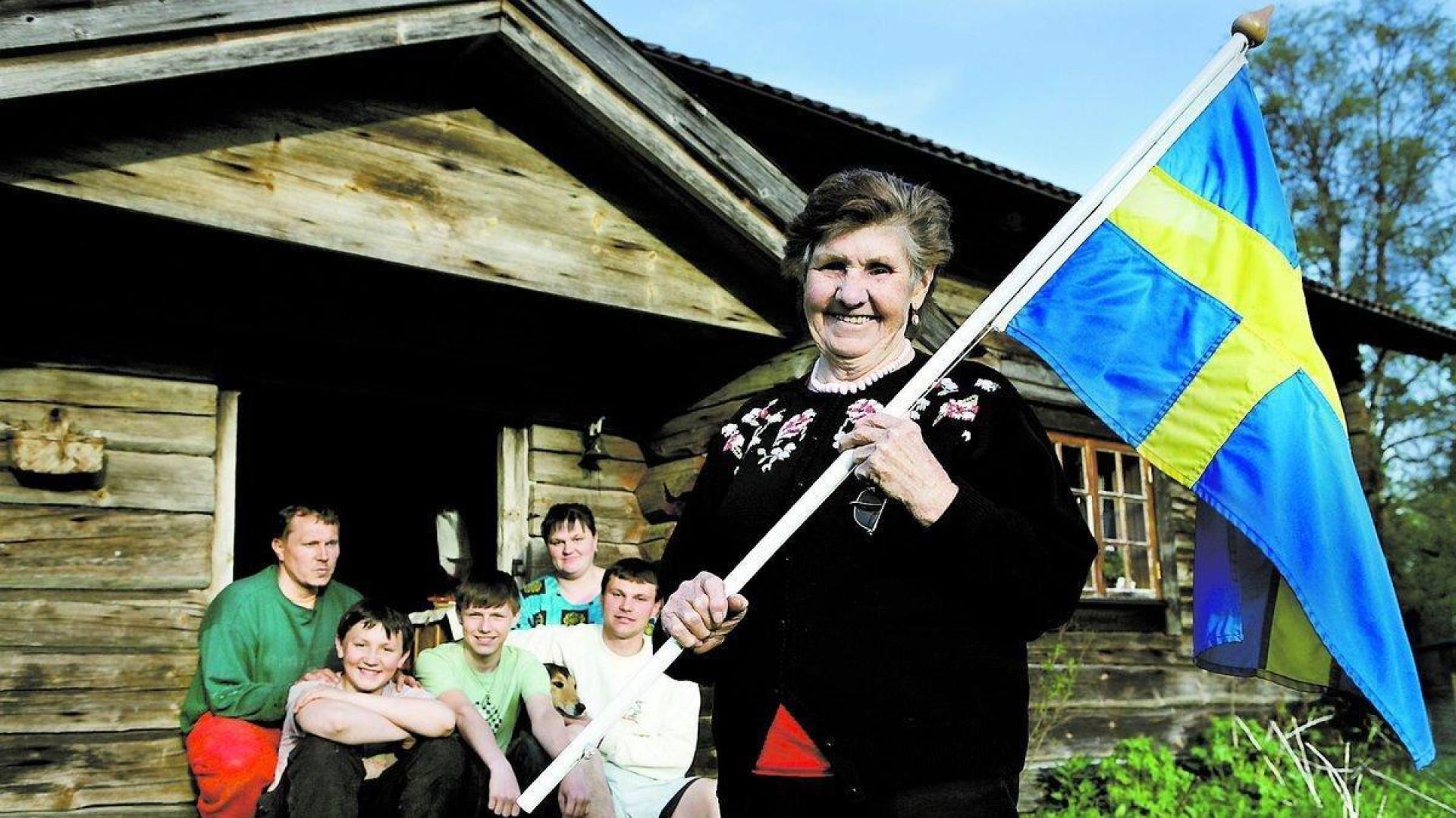 Una familia en Gammalsvenskby (Ucrania), con la bandera de Suecia