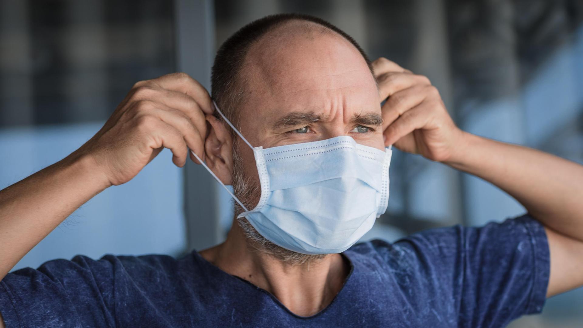 Un hombre, ajustándose una mascarilla