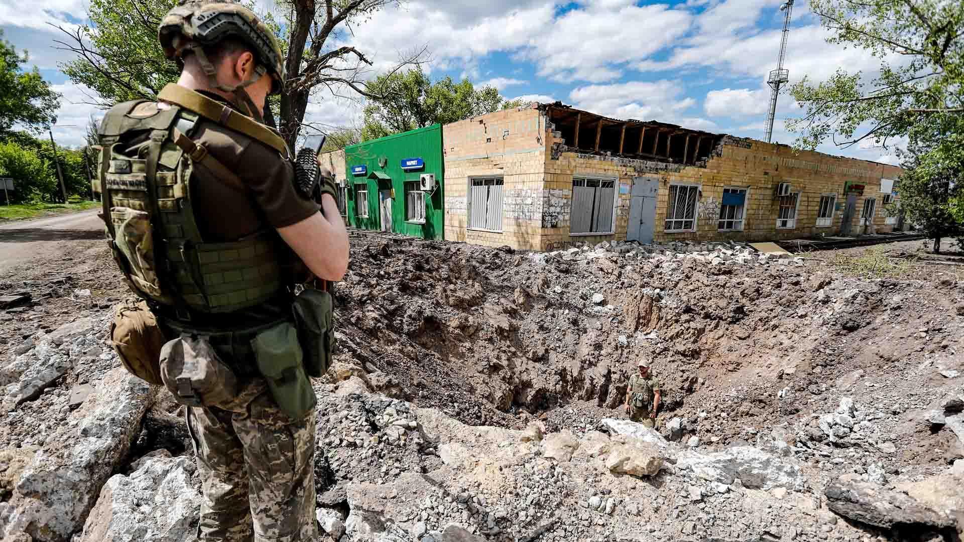 Un soldado ucraniano inspecciona un enorme agujero de un ataque aéreo ruso