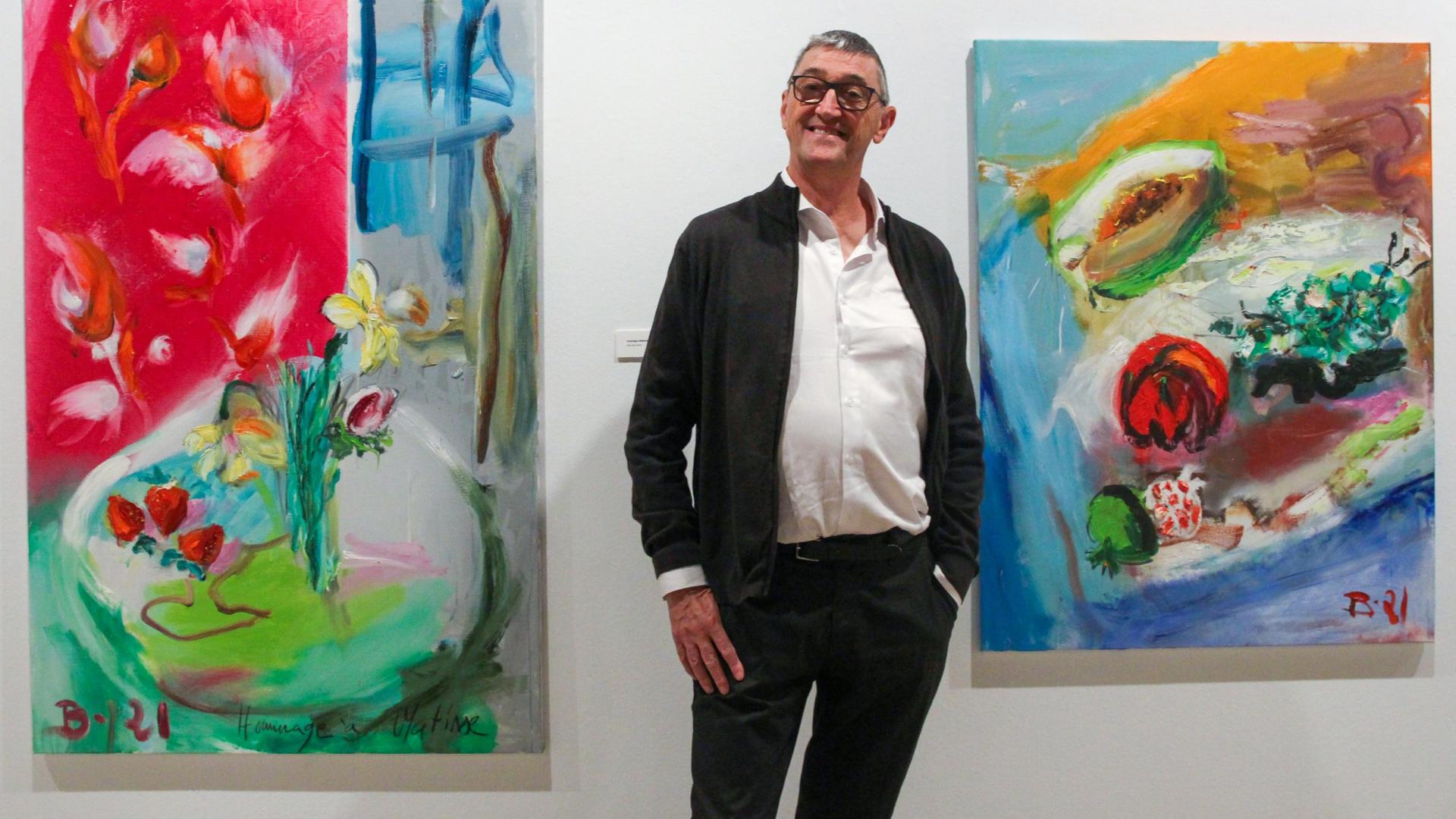 El pintor Juan Belzunegui, natural de Carcastillo, posa junto a dos de las cuarenta obras que podrán visitarse hasta el 26 de junio