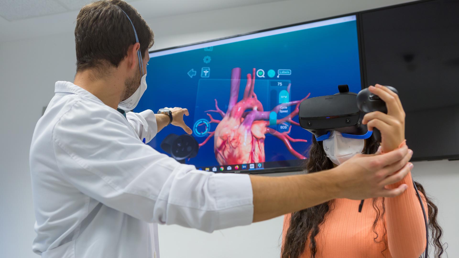 Un profesor de la Facultad de Medicina guía a una alumna en el uso de un simulador de realidad virtual para estudiar las patologías cardiacas