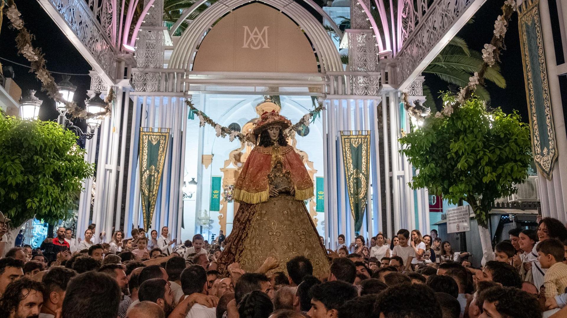 La virgen del Rocío, vestida de Pastora, procesiona a hombros de los almonteños por las calles de Almonte (Huelva).